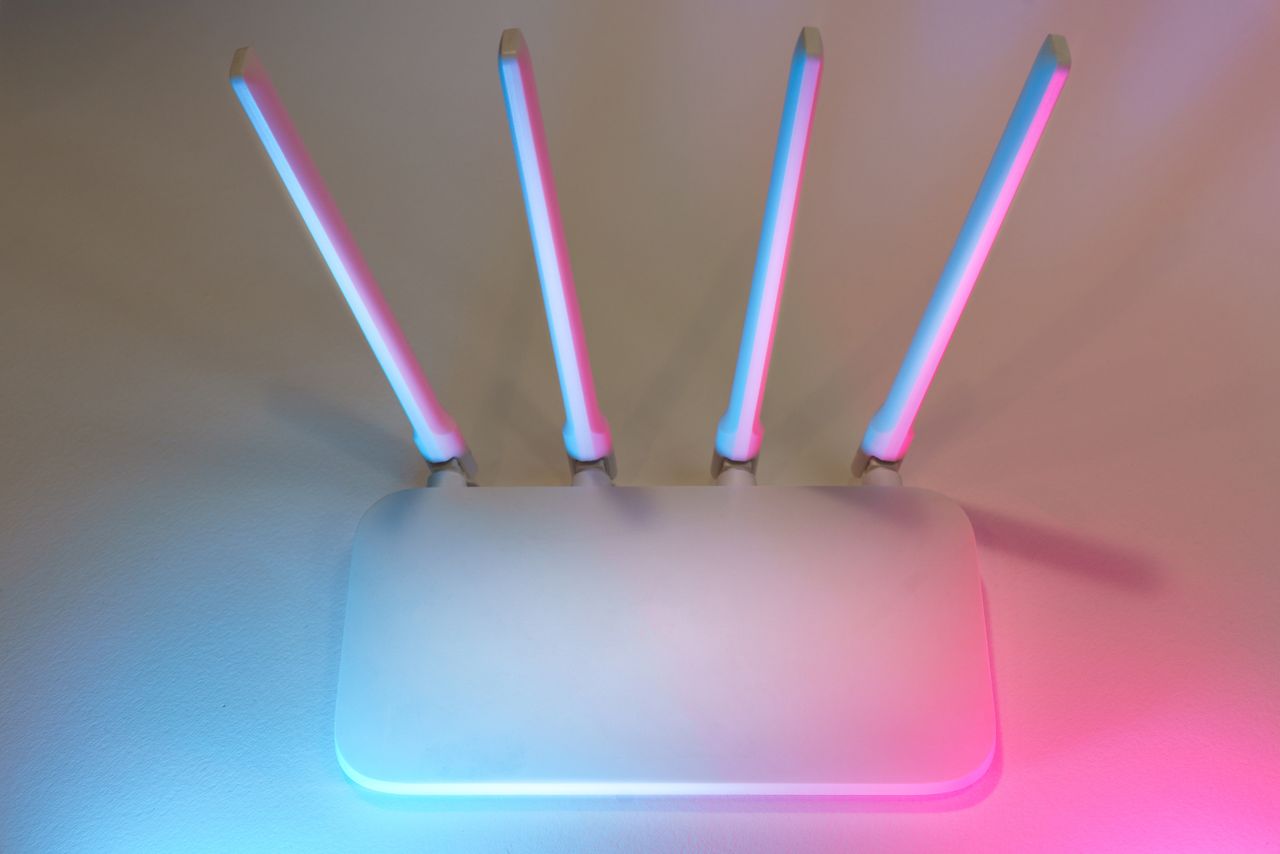 Mastering the First Impression: Your intriguing post title goes here Sleek white wireless router with four antennas emitting soft blue and pink light.